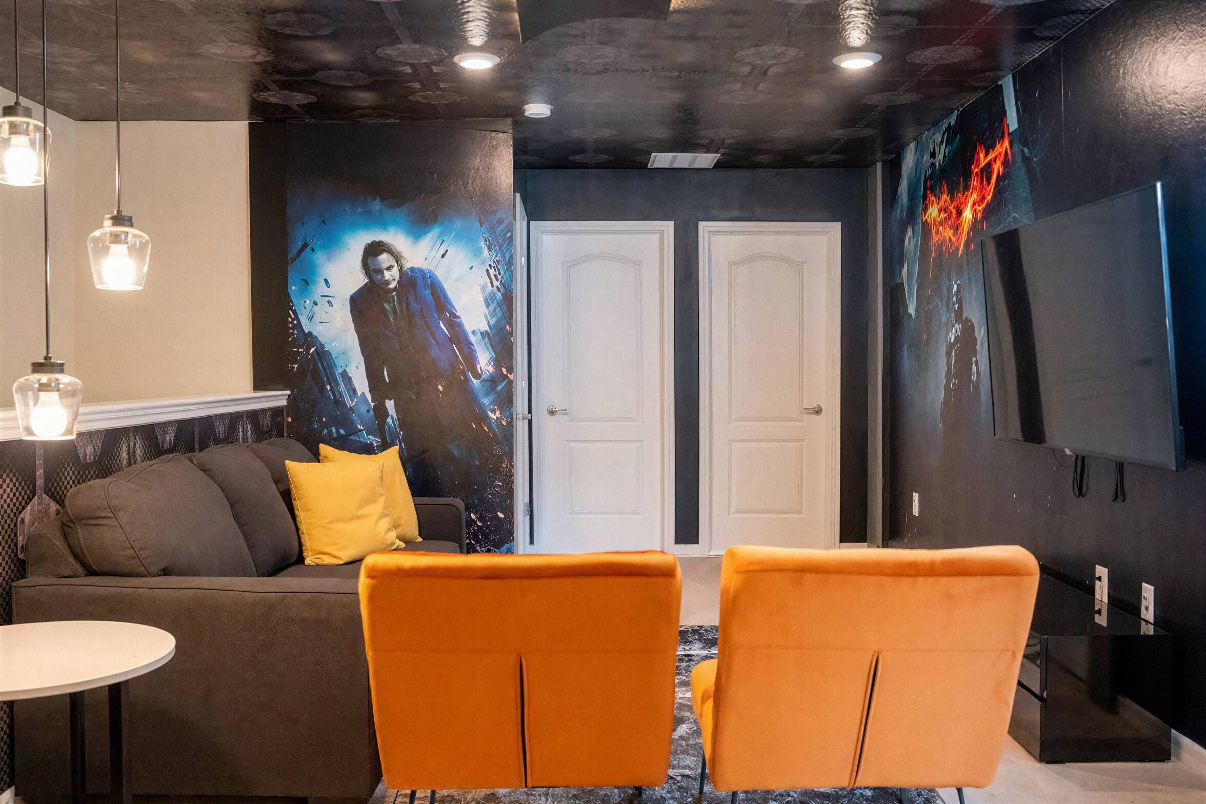 Una habitación moderna con sofá, dos sillones, una mesa y una pared con un cartel grande.