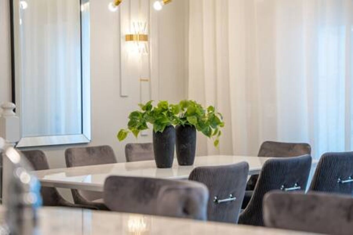 Una sala de conferencias moderna con una mesa redonda, sillas tapizadas de gris y dos plantas en macetas.
