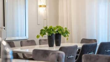 Una sala de conferencias moderna con una mesa redonda, sillas tapizadas de gris y dos plantas en macetas.