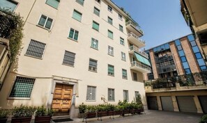 A multi-story building with a beige facade, multiple windows with metal grilles, and a central entrance with a wooden door. - Charming 2-bedroom house in lovely Roma with AC, WiFi (Roma)