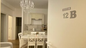 A modern apartment with a dining area, a chandelier, and a kitchen in the background. - Charming 2-bedroom house in lovely Roma with AC, WiFi (Roma)