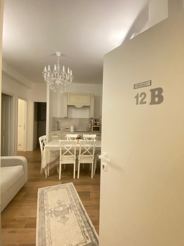 A modern apartment with a dining area, a chandelier, and a kitchen in the background. - Charming 2-bedroom house in lovely Roma with AC, WiFi (Roma)