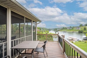Una terraza de madera con una mesa y sillas, con vista a un río y vegetación.