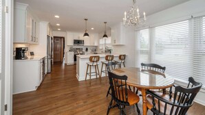 A modern kitchen with white cabinets, a central island, and bar stools. - Tallen Manor & Retreat (Hamilton)