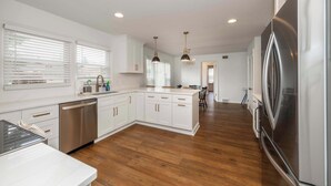 A modern kitchen with white cabinetry, stainless steel appliances, and wooden flooring. - Tallen Manor & Retreat (Hamilton)