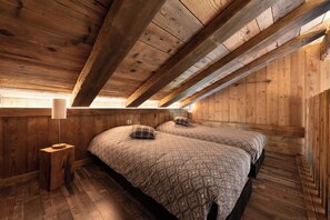 A wooden room with two beds, a nightstand, and a lamp. - Chalet "Le Cocoonid" - Bain Nordique - Sauna (Ventron)