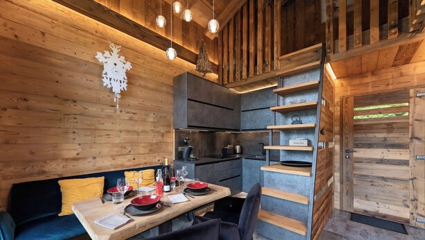 Ein gemütliches Blockhaus-Interieur mit Essbereich, Holzwänden und einer integrierten Küche.