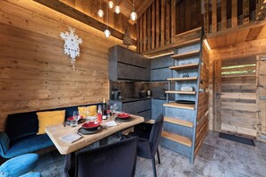Un intérieur de chalet chaleureux avec un coin repas, des murs en bois et une cuisine intégrée.