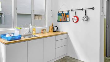 A modern kitchen with a window, a sink, a countertop, and a hanging pot rack.