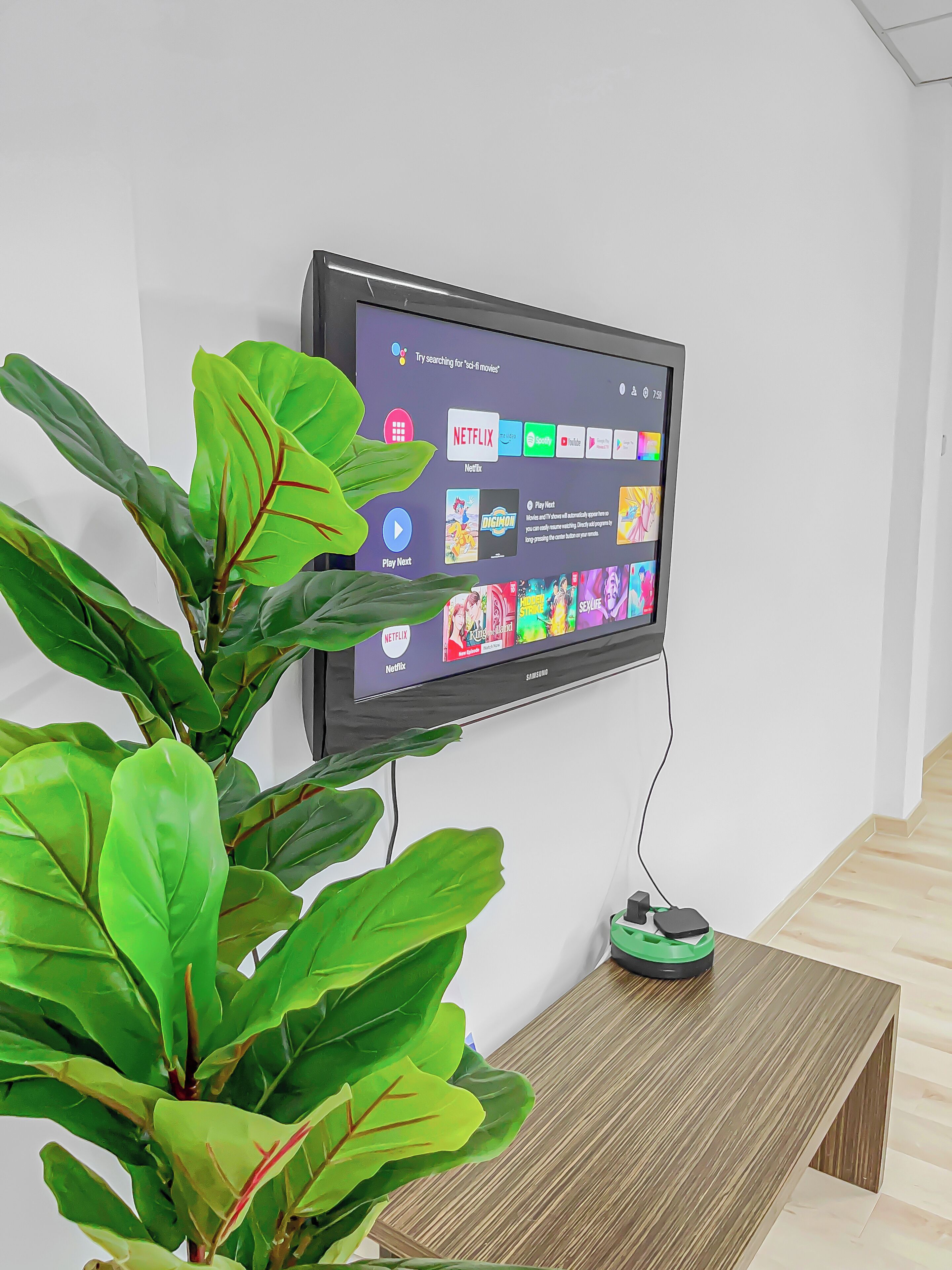 A flat-screen TV mounted on a wall displaying a streaming service interface with various content options.