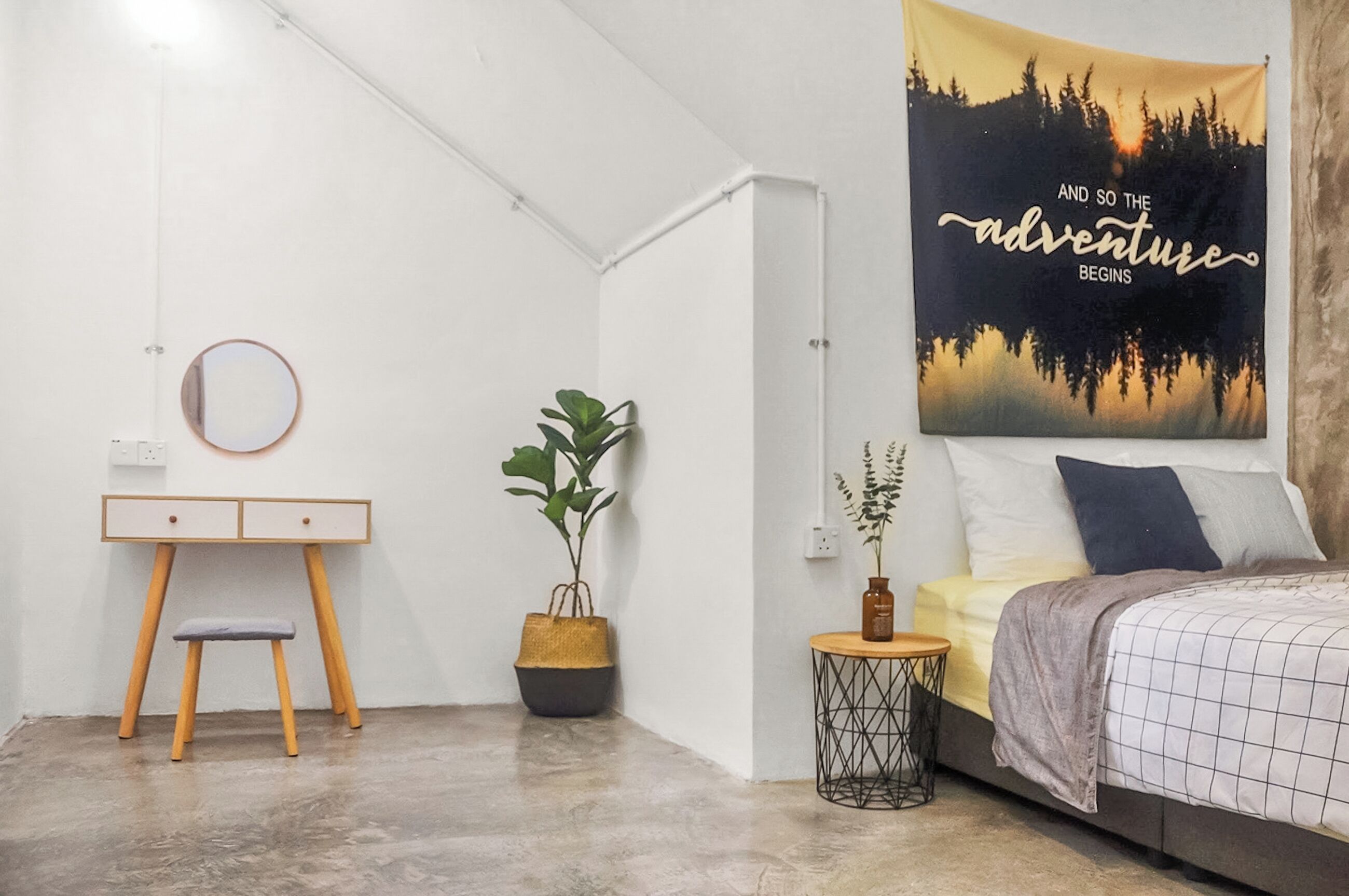 Un dormitorio con una cama, un escritorio, una silla, una planta en maceta y un cartel en la pared.