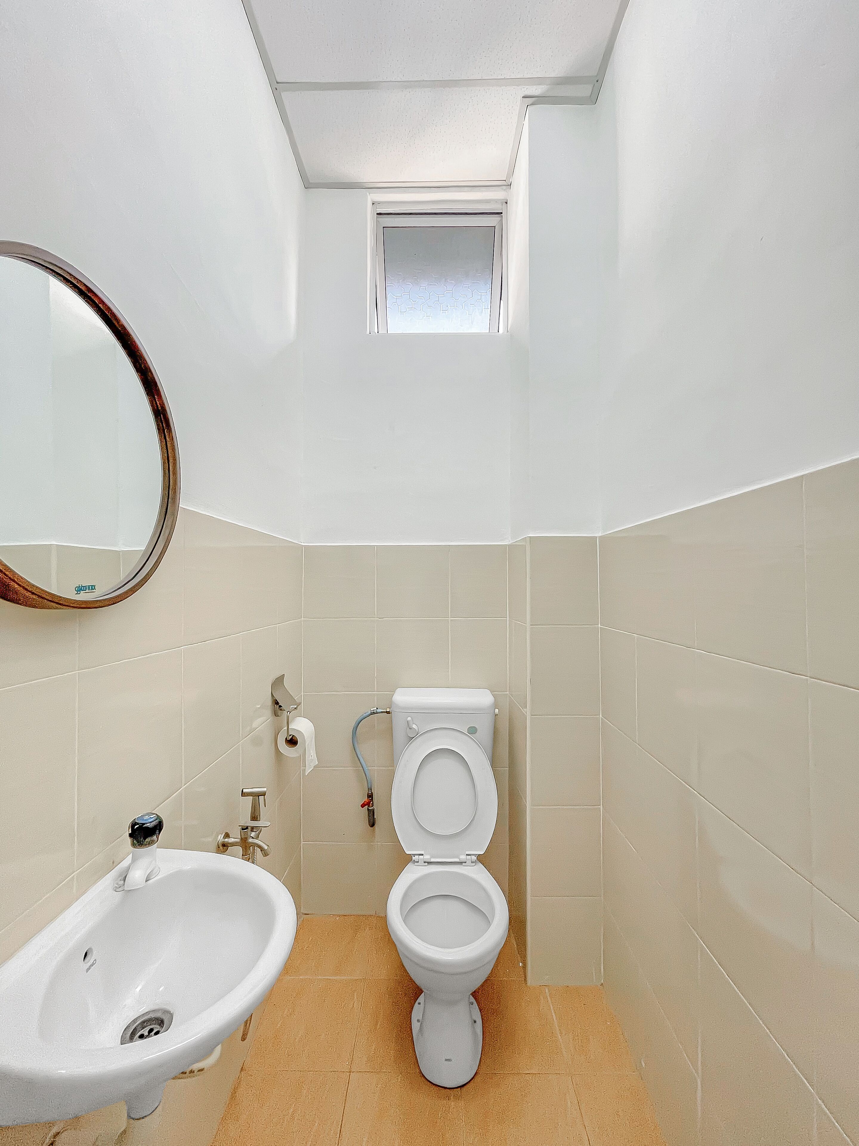 A small bathroom with a toilet, sink, and a mirror.