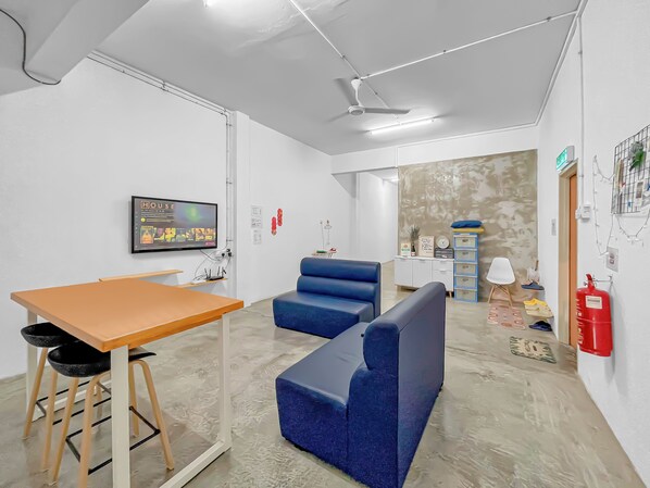 Una habitación moderna con una mesa de madera, un sofá azul y un ventilador de techo.