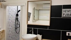 A bathroom with a toilet, a sink, a mirror, and a shower. - Napoli Historic center Tribunali Duomo house (Napoli)