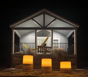 A covered outdoor area with a wooden deck, a yellow slide, and three lit candles on the ground.