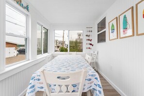 A room with a dining table, chairs, and a view through large windows. - Blue Tides (Wells)