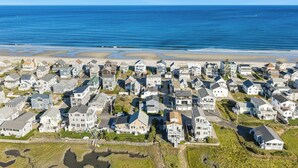 A coastal residential area with houses, a beach, and a clear blue sky.