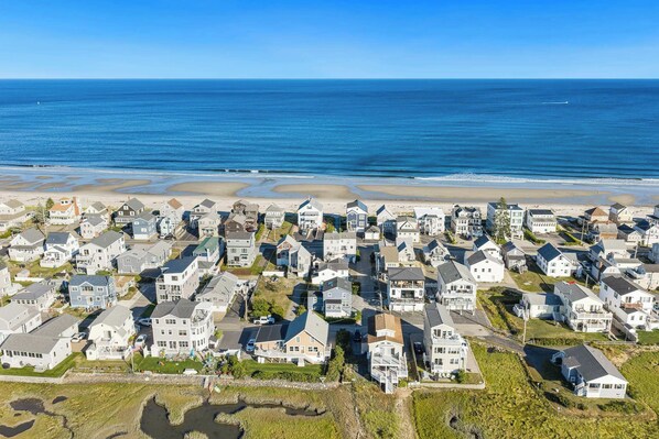 Zona residencial costera con casas, una playa y un cielo azul despejado.