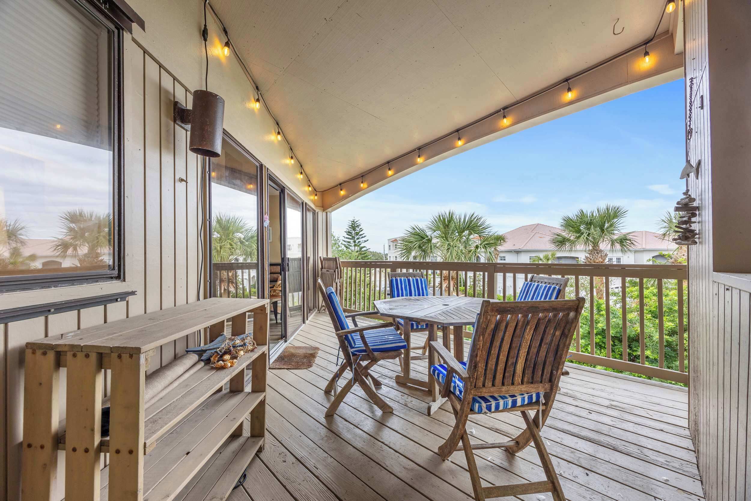 A wooden deck with a table and chairs, a bench, and string lights.