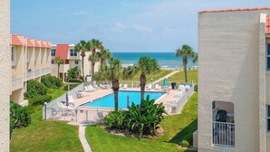 Un hôtel doté d’une piscine, de palmiers et offrant une vue sur l’océan.