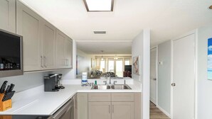 Een moderne keuken met een centraal eiland, inbouwapparatuur en een ruime voorraadkast.