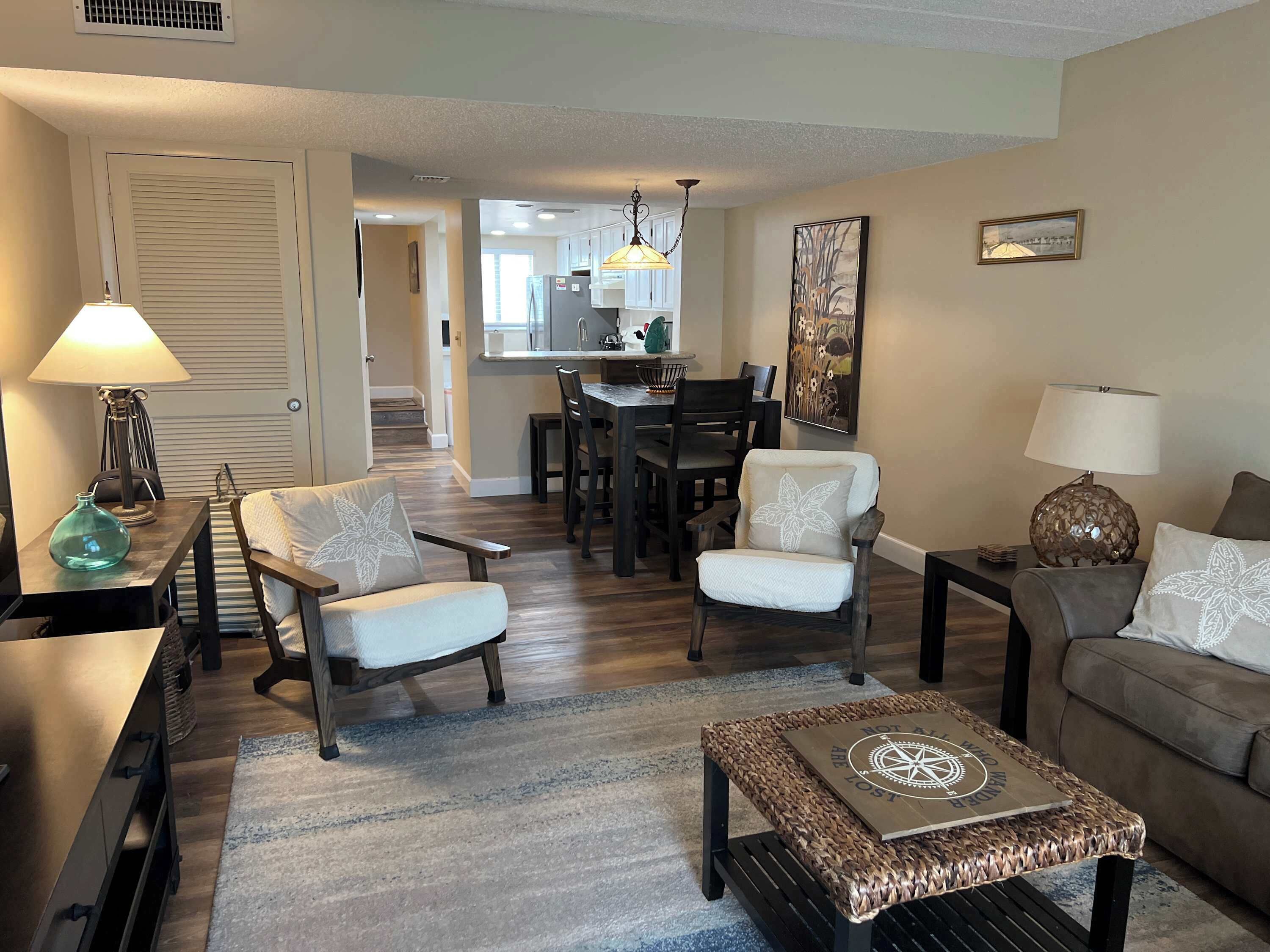 A living room with a sofa, armchairs, a coffee table, and a dining area with a table and chairs.