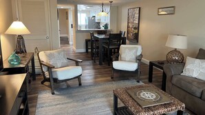 Una sala de estar con sofá, sillones, una mesa de centro y un comedor con mesa y sillas.