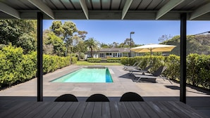 Una piscina cubierta al aire libre con sillones de descanso y una pérgola.