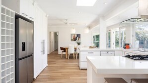 Una cocina moderna con una isla central, electrodomésticos de acero inoxidable y un comedor con luz natural.