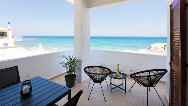 A balcony with a view of the sea, a table with chairs, and a potted plant. - Nova Sea View Apartment Seafront (Kokkini Hani)