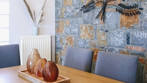 A dining area with a stone wall, a radiator, and a table set with breakfast items. - Nova Sea View Apartment Seafront (Kokkini Hani)
