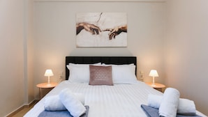 A hotel room with a large bed, two bedside lamps, a painting above the bed, and towels on the bed. - Nova Sea View Apartment Seafront (Kokkini Hani)