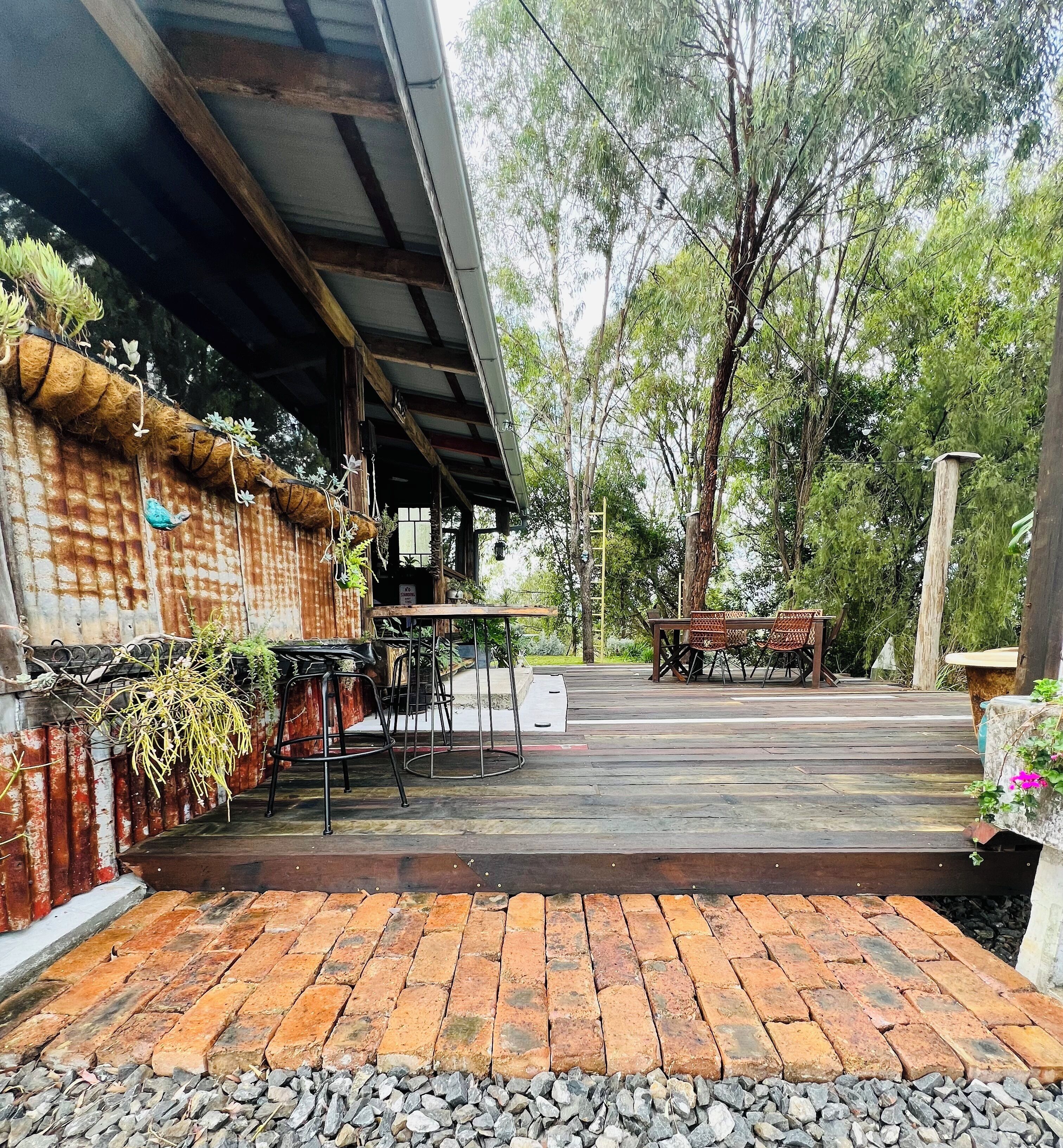 A rustic outdoor seating area with a brick floor, metal chairs, and a table.