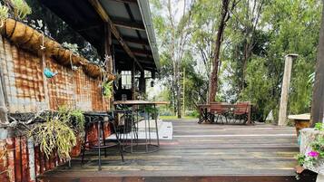 A rustic outdoor seating area with a brick floor, metal chairs, and a table.