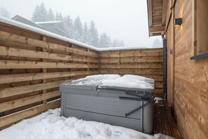 Eine Holzblockhütte mit Sauna, verschneitem Dach und Holzzaun.