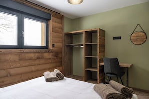 Ein Zimmer mit einem Bett, einem Holzschrank, einem Schreibtisch und einem Stuhl.