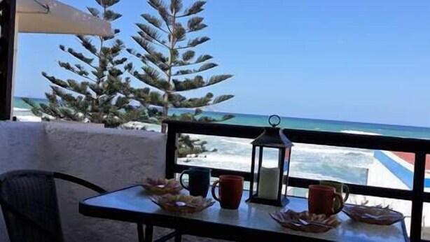 A table with a view of the ocean, a lantern, and a chair.