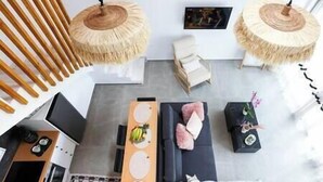 A modern living room with a sofa, two side tables, and a coffee table. There are two hanging lamps with natural fiber shades.