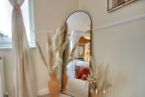 A mirror reflecting a room with pampas grass in vases, a window with a curtain, and a bed with a white canopy. - Costal Bohemian Retreat Central Southsea (Portsmouth)