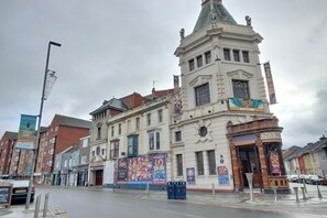 A historic building with a prominent clock tower, a Kings Theatre sign, and various posters advertising events. - Costal Bohemian Retreat Central Southsea (Portsmouth)