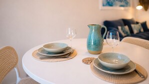A dining table with plates, a pitcher, and glasses, surrounded by wicker chairs.