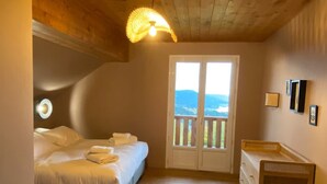 Quarto com cama, cômoda, tapete e vista através de uma porta.