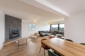 A modern living room with a fireplace, a dining area, and a sofa set. - LE PERCHOIR - 14 guests - Lake view - Sauna, Gérardmer (Gérardmer)
