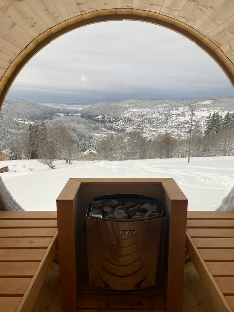 A wooden cabin with a fireplace, a wooden bench, and a view of a snowy landscape.