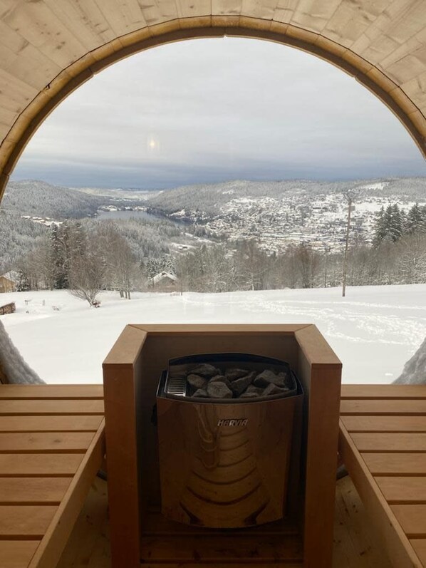 A wooden cabin with a fireplace, a wooden bench, and a view of a snowy landscape.