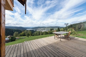A wooden deck with a table and chairs, overlooking a valley and a lake. - LE PERCHOIR - 14 guests - Lake view - Sauna, Gérardmer (Gérardmer)