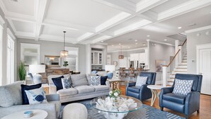 A spacious living room with a grey sofa, blue armchairs, and a glass coffee table. - Kiva Dunes Luxury Retreat | Private Pool | Gulf Views (Gulf Shores)
