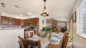 A spacious dining area with wooden furniture, a chandelier, and a view of the kitchen and living room. - Pine Cliff (Flagstaff)