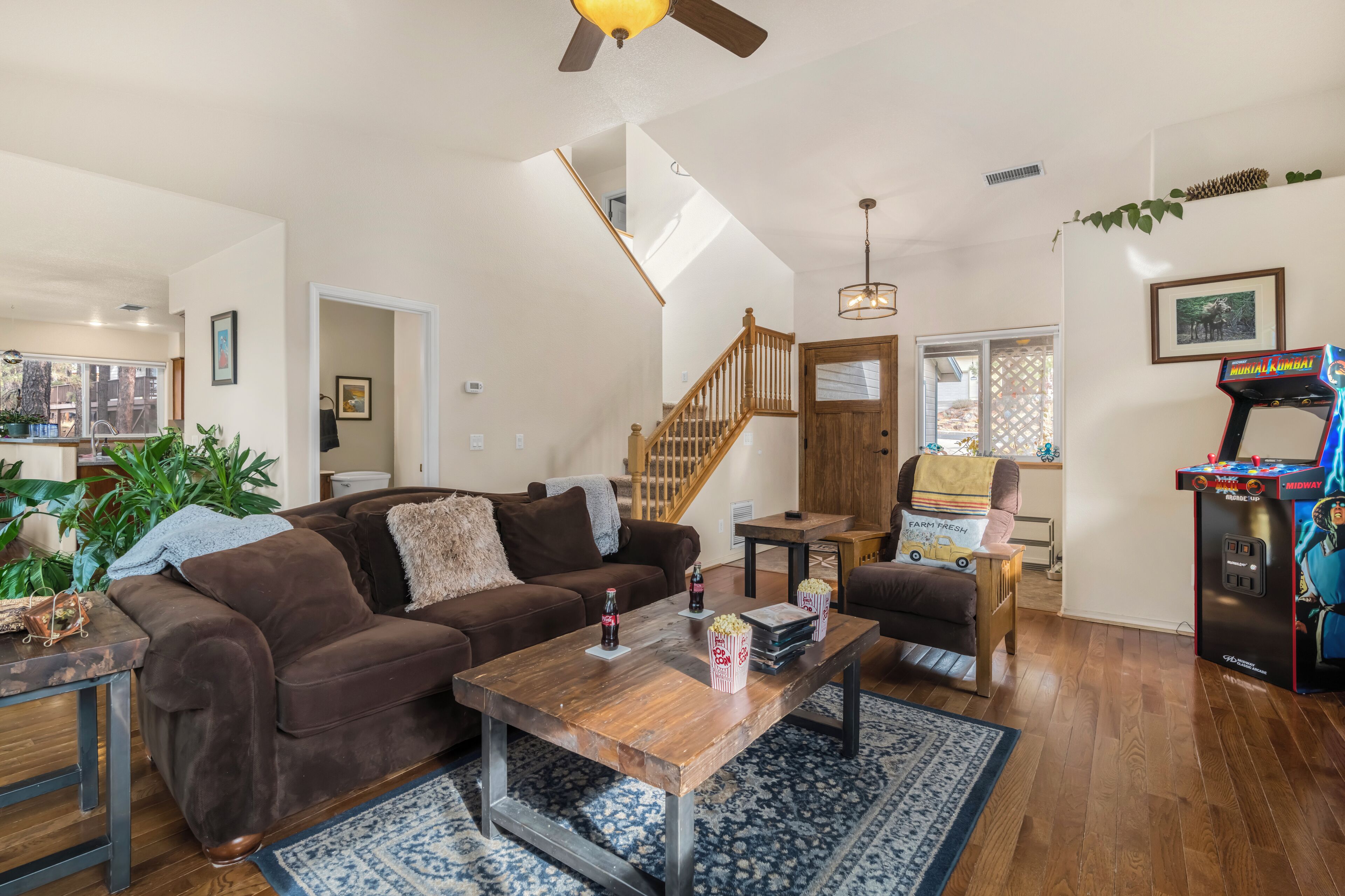 A spacious living room with a brown couch, wooden coffee table, and a retro arcade machine.