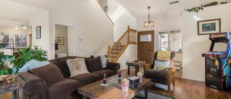 A spacious living room with a brown couch, wooden coffee table, and a retro arcade machine.